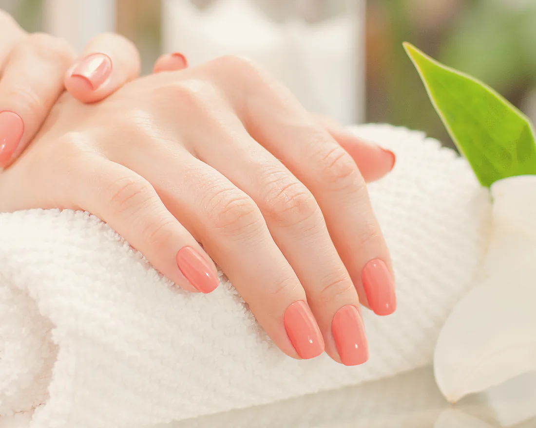 A finished coral manicure resting on a white towel