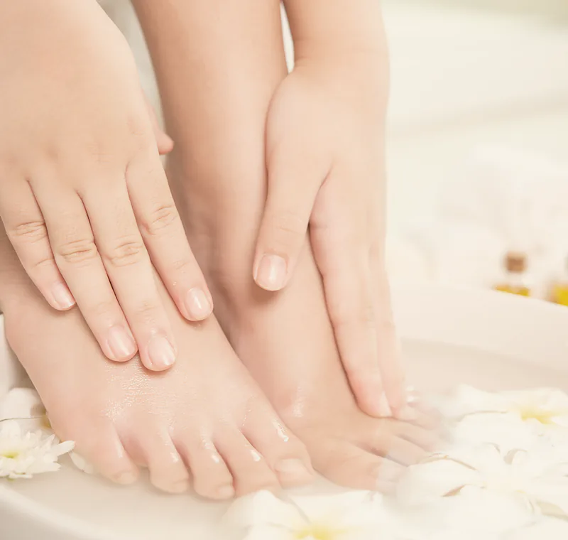Feet soaking in a flower-strewn bowl during a pedicure