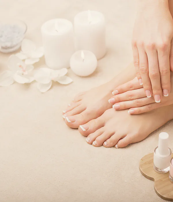 Finished hands and feet beside spa candles and blossom