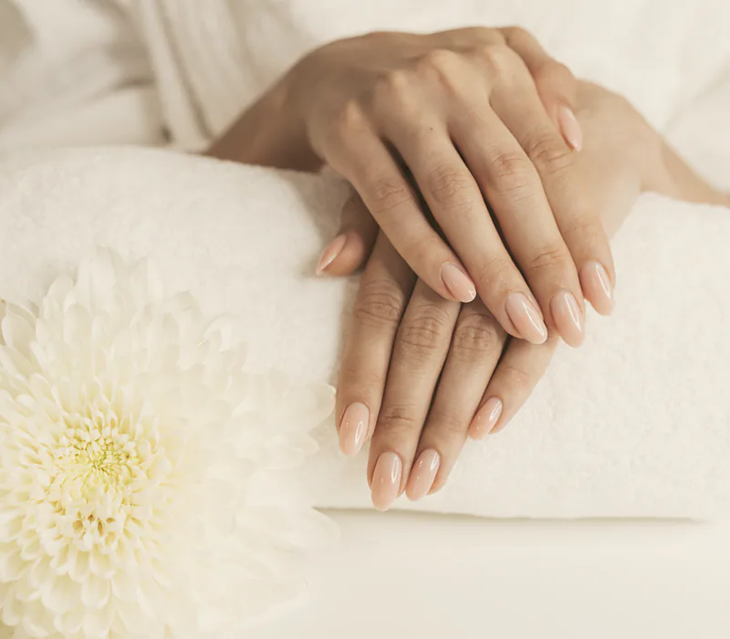 A finished nude manicure resting on a folded white towel